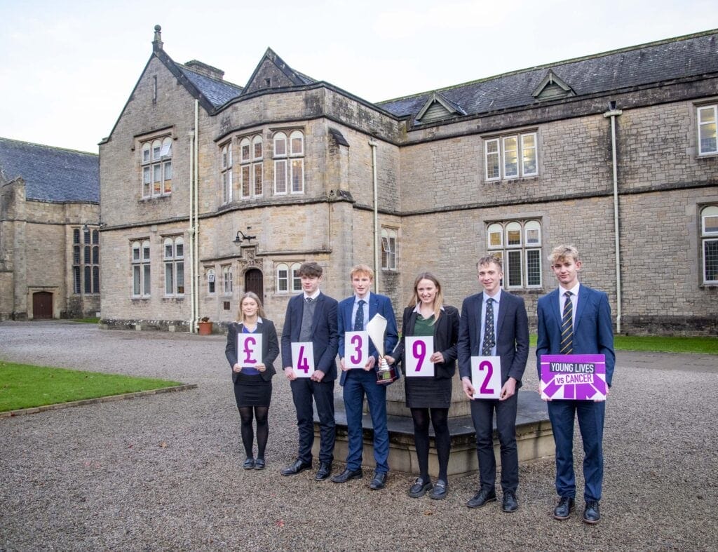 Six pupils proudly standing with the total raised for charity