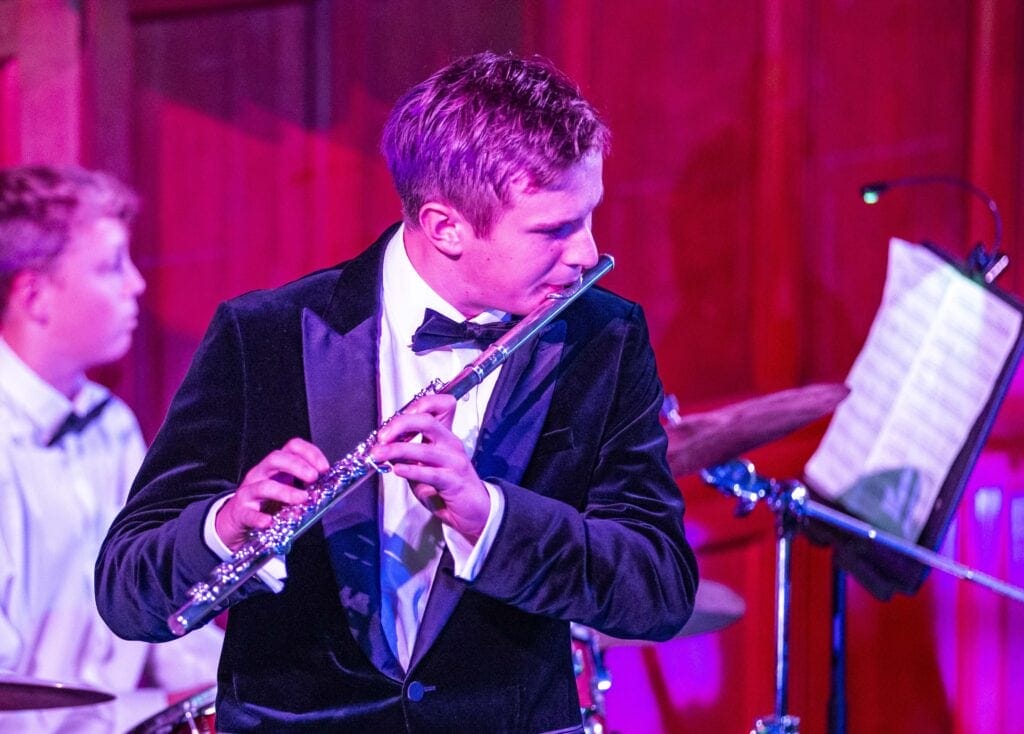 Archie plays the flute on stage